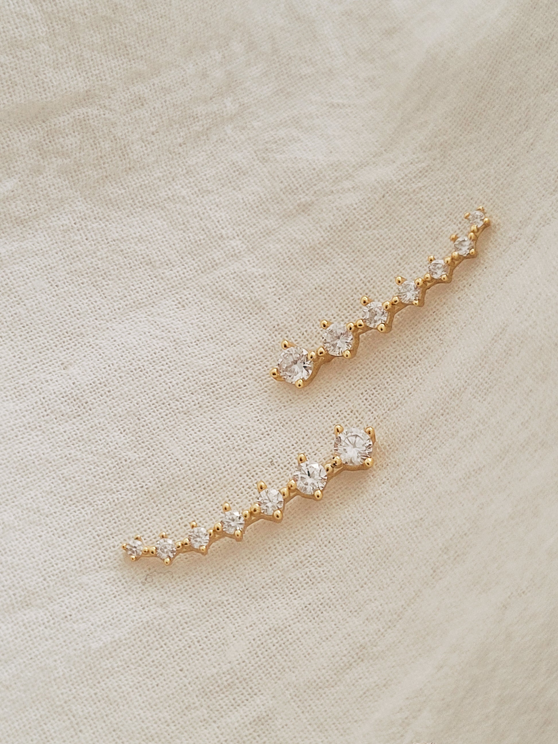 A pair of gold-plated sterling silver climber earrings adorned with cubic zirconia stones, displayed on a clean white surface.