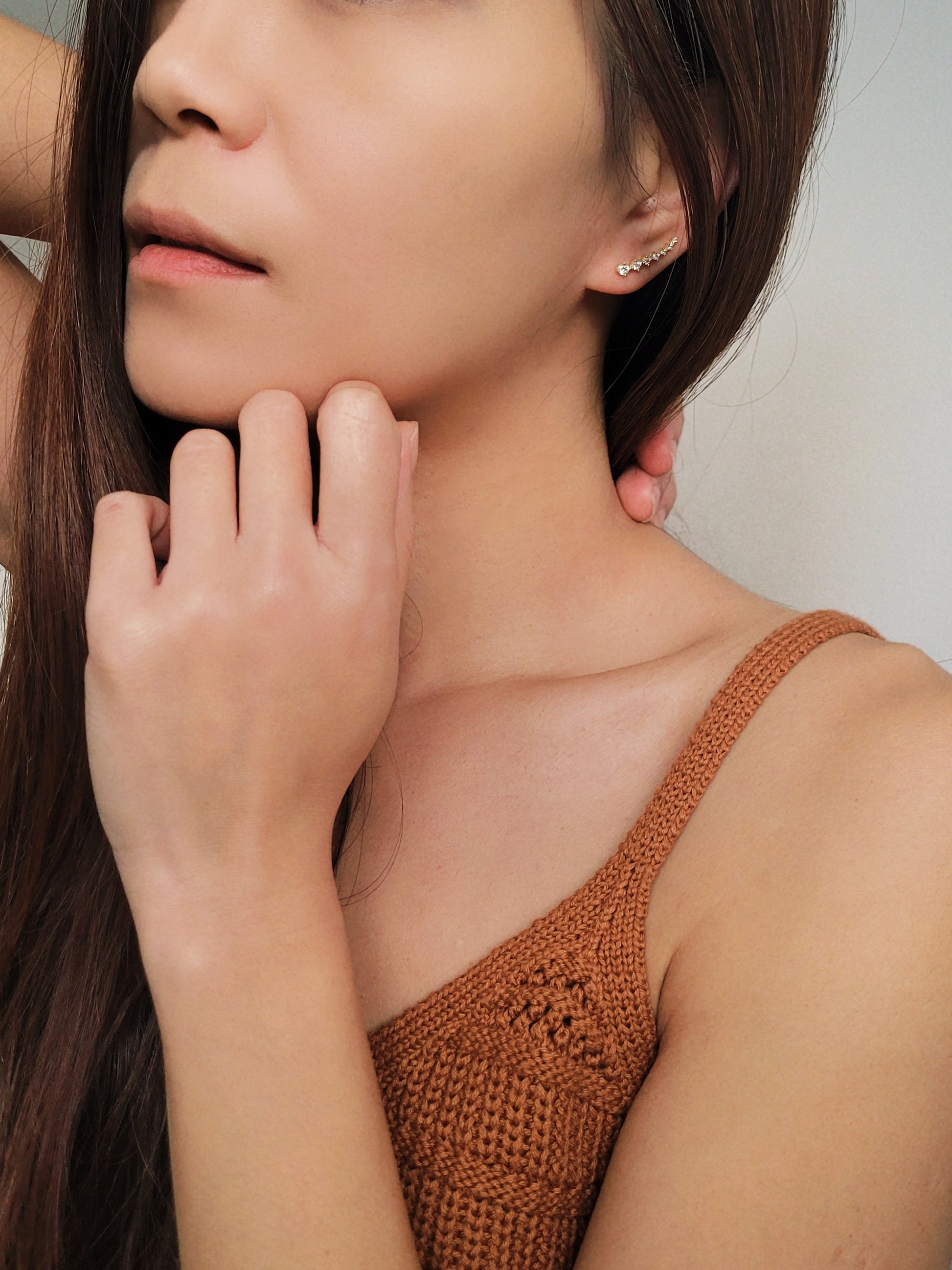 Close-up of a woman&#39;s ear wearing an 18K gold-plated cubic zirconia climber earring, highlighting the elegant and minimalist design.