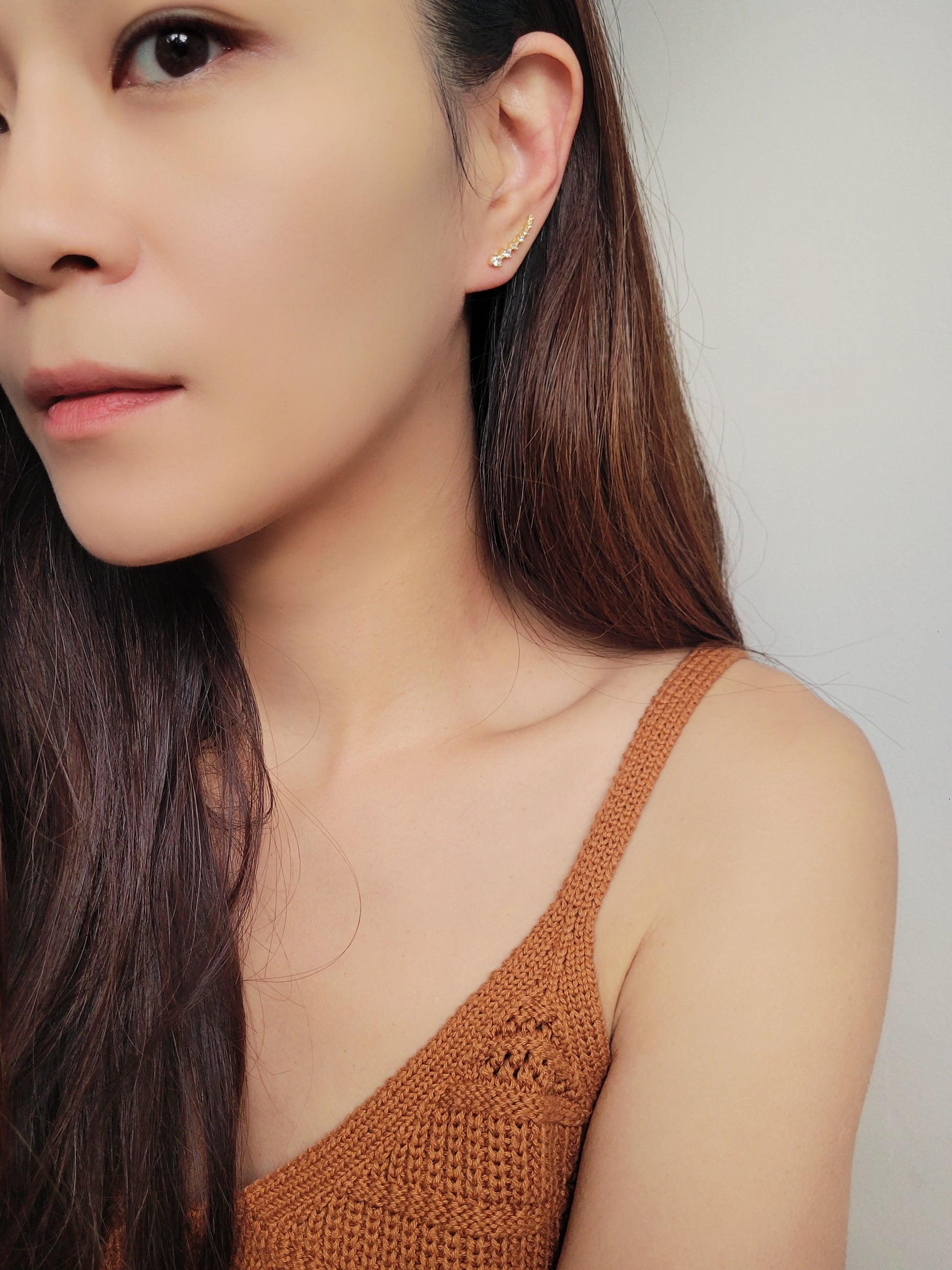 Close-up of a woman&#39;s ear wearing an 18K gold-plated cubic zirconia climber earring, highlighting the elegant and minimalist design.