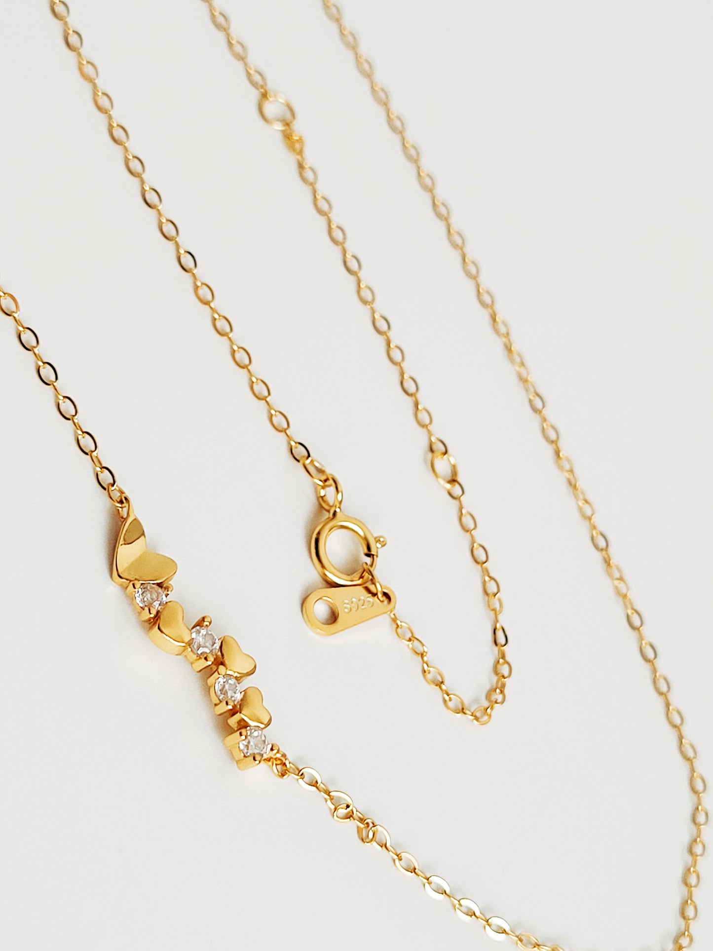 Close-up of a dainty gold necklace with heart charms and sparkling diamond accents, perfect for weddings, bridal showers, and Valentine’s Day.