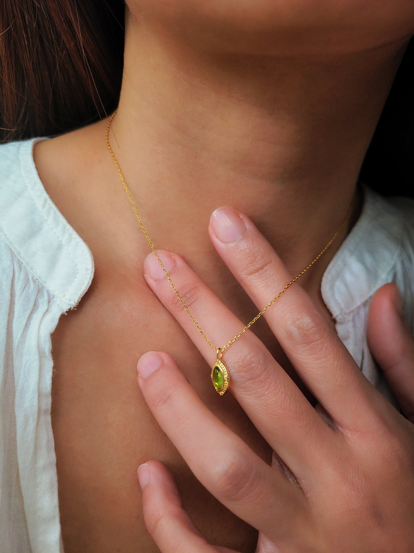 A woman wearing an elegant green gemstone necklace with intricate gold detailing, perfect for boho and vintage-style jewelry lovers.