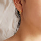 A close-up of a gold huggie earring with a delicate dangling flower charm, crafted in gold plated sterling silver. The intricate flower design adds a touch of femininity, making them ideal as wedding jewelry, a bridesmaid gift, or a thoughtful present for her.