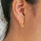 Side view of a beautiful flower earrings on huggie hoops worn on a woman's ear.