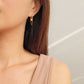 Close-up of a pair of gold double chain huggie earrings with a CZ diamond drop. Crafted in gold plated sterling silver, boho chic summer look.