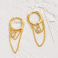 Close-up of a pair of gold double chain huggie earrings with a CZ diamond drop. Crafted in gold plated sterling silver, boho chic summer look.