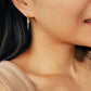 Close-up of a pair of gold double chain huggie earrings with a CZ diamond drop. Crafted in gold plated sterling silver, boho chic summer look.
