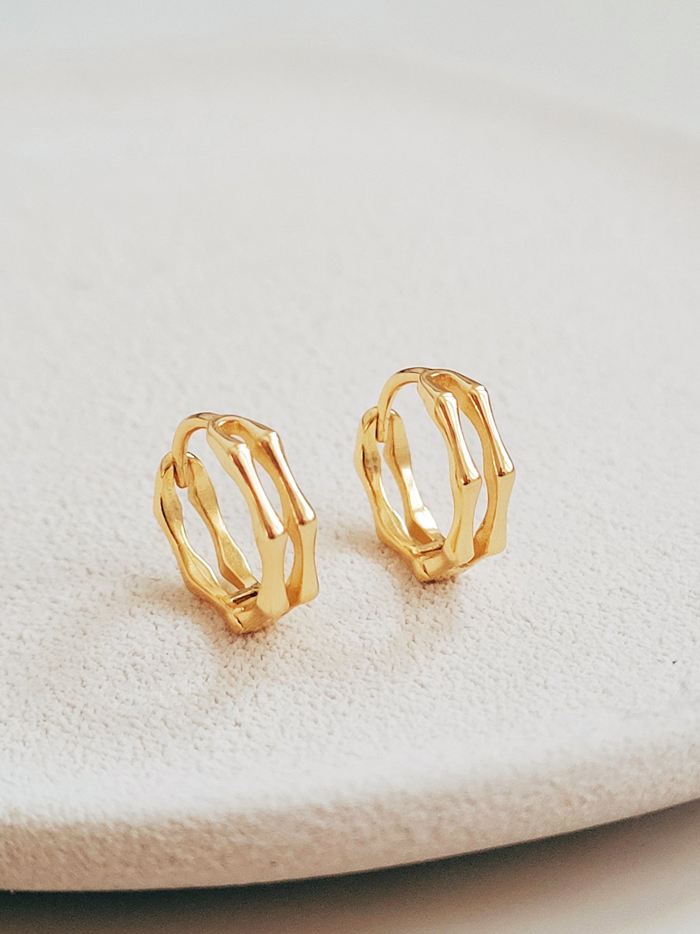 Close-up image of double hoop huggie earrings in octagon shape, featuring a minimalist gold geometric design, worn on an ear. Perfect for everyday wear.
