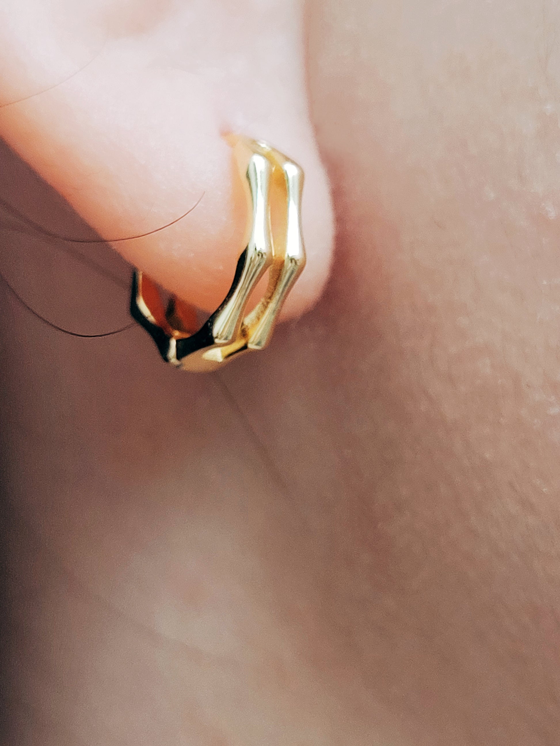 Close-up image of double hoop huggie earrings in octagon shape, featuring a minimalist gold geometric design, worn on an ear. Perfect for everyday wear.