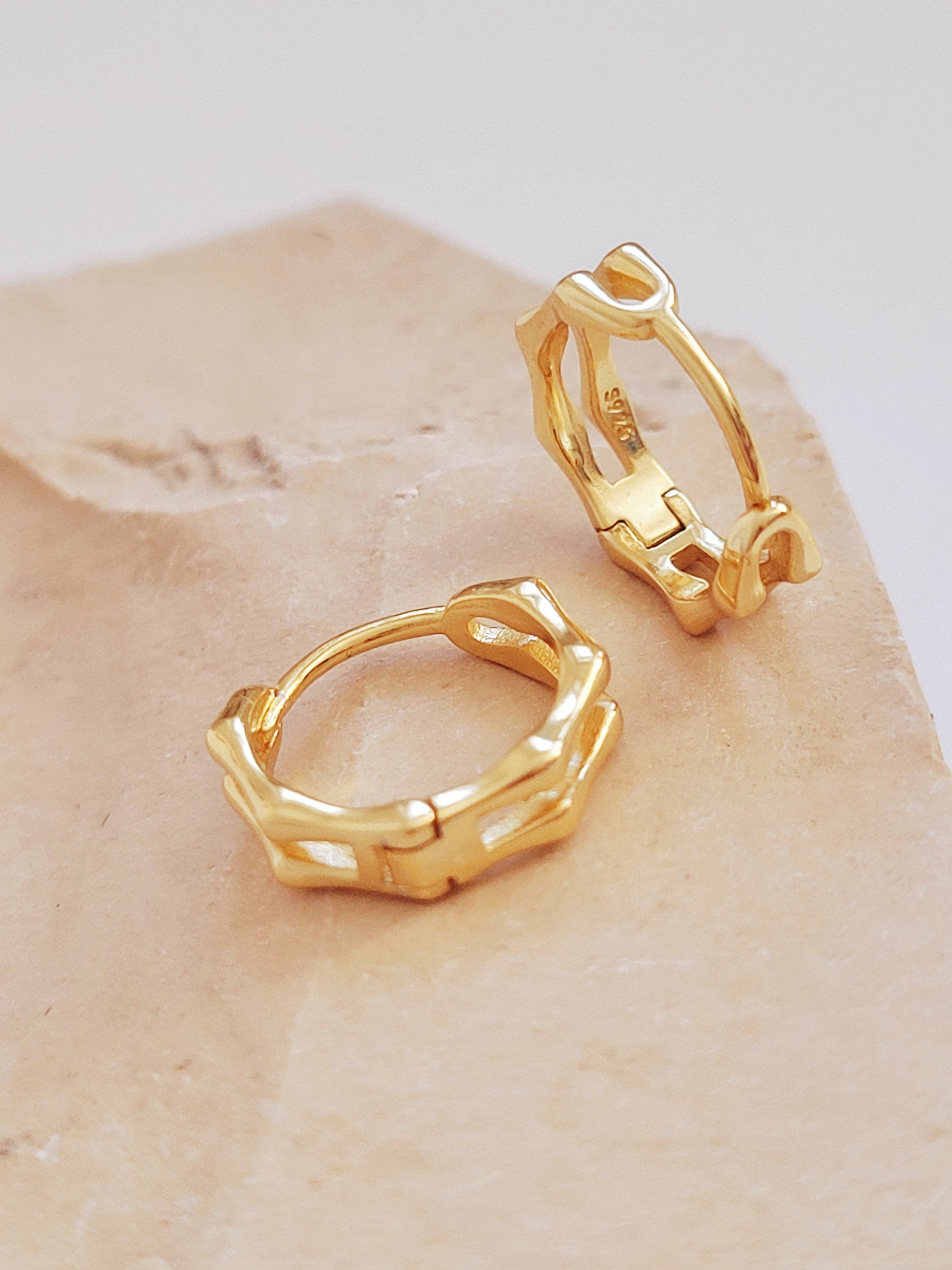 Close-up image of double hoop huggie earrings in octagon shape, featuring a minimalist gold geometric design, worn on an ear. Perfect for everyday wear.