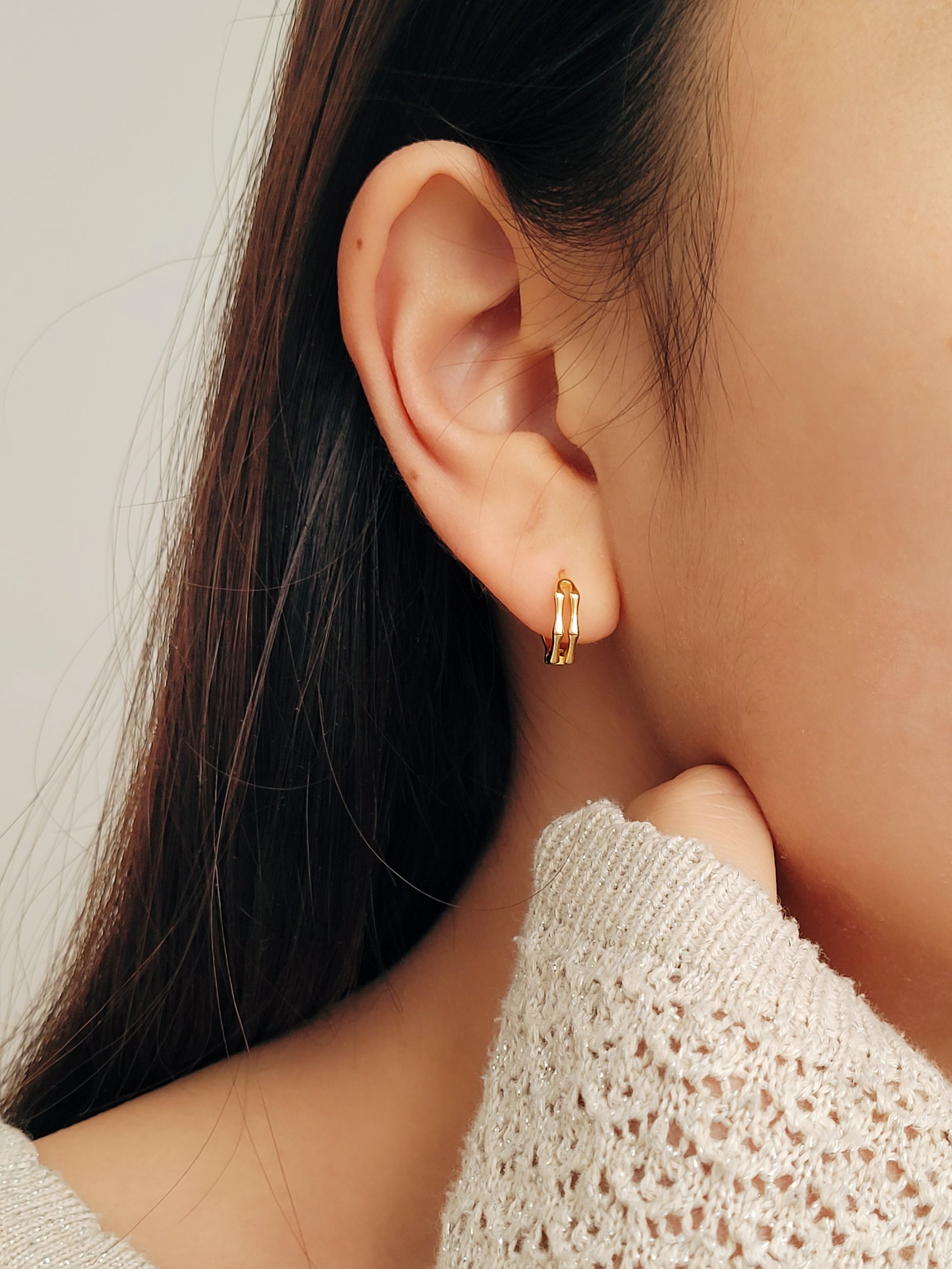 Close-up image of double hoop huggie earrings in octagon shape, featuring a minimalist gold geometric design, worn on an ear. Perfect for everyday wear.