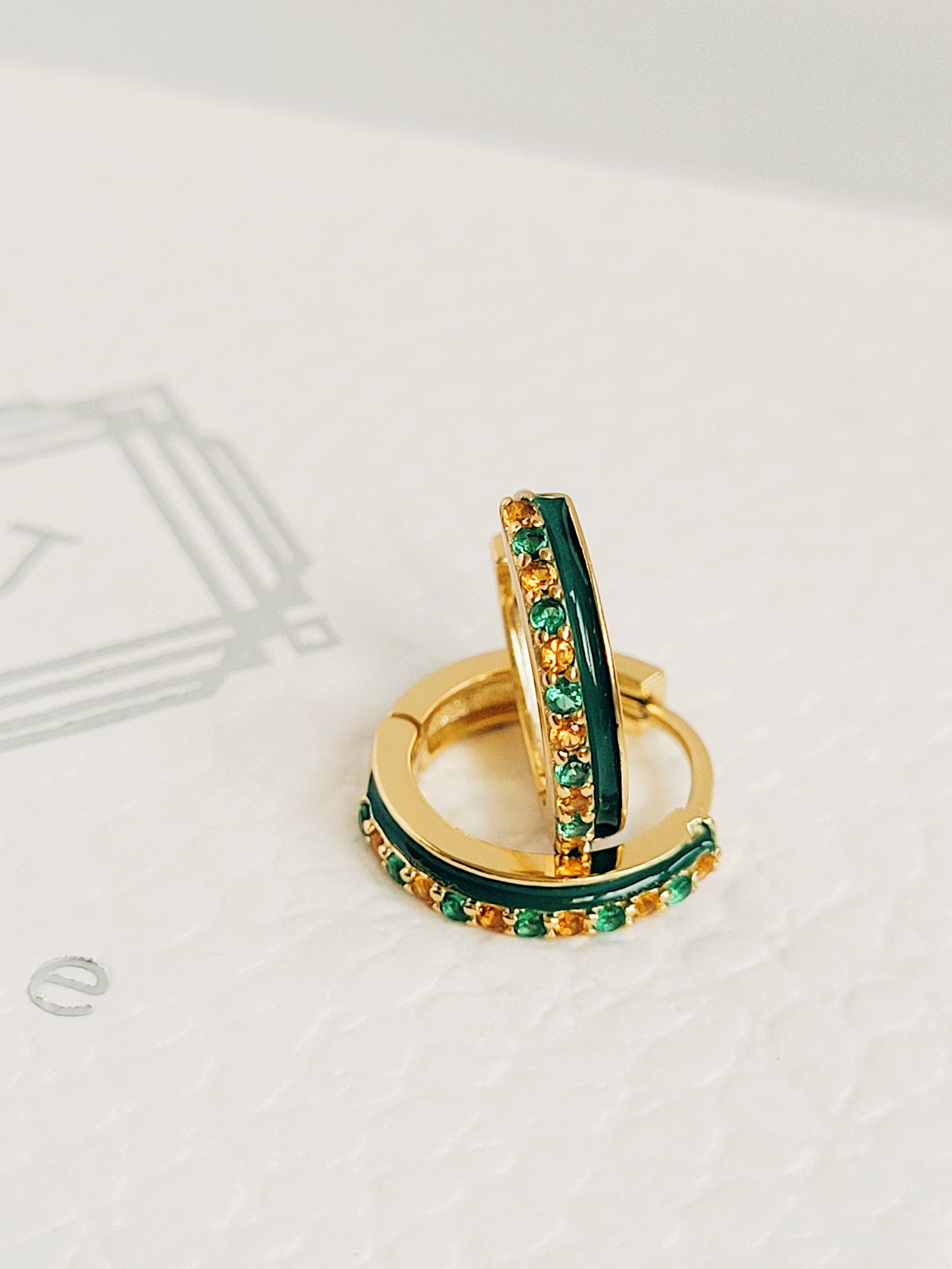 Close-up of emerald green enamel huggie hoop earrings with gold-plated and zircons detailing, showcasing its elegance minimalist style.