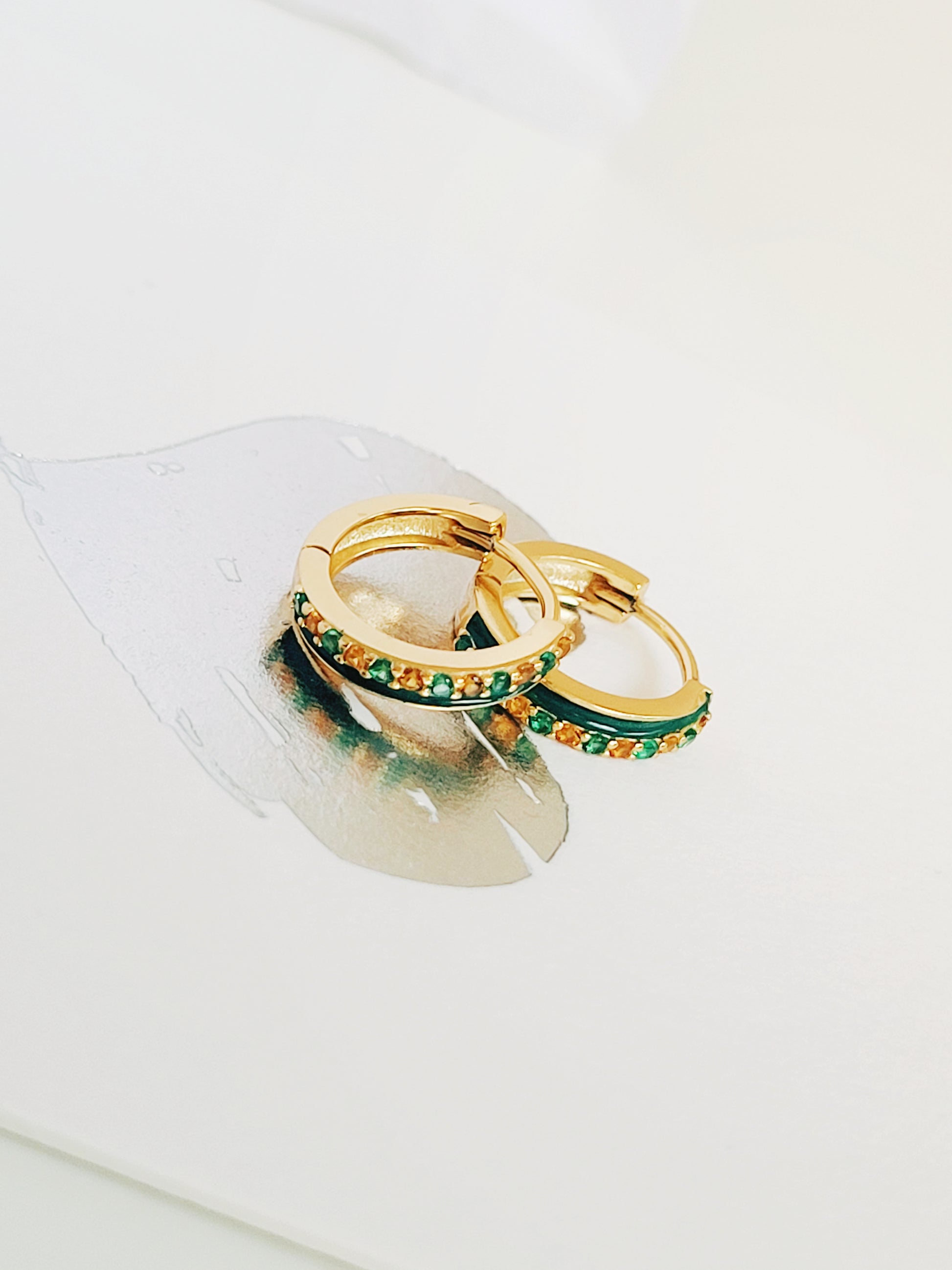 Close-up of emerald green enamel huggie hoop earrings with gold-plated and zircons detailing, showcasing its elegance minimalist style.