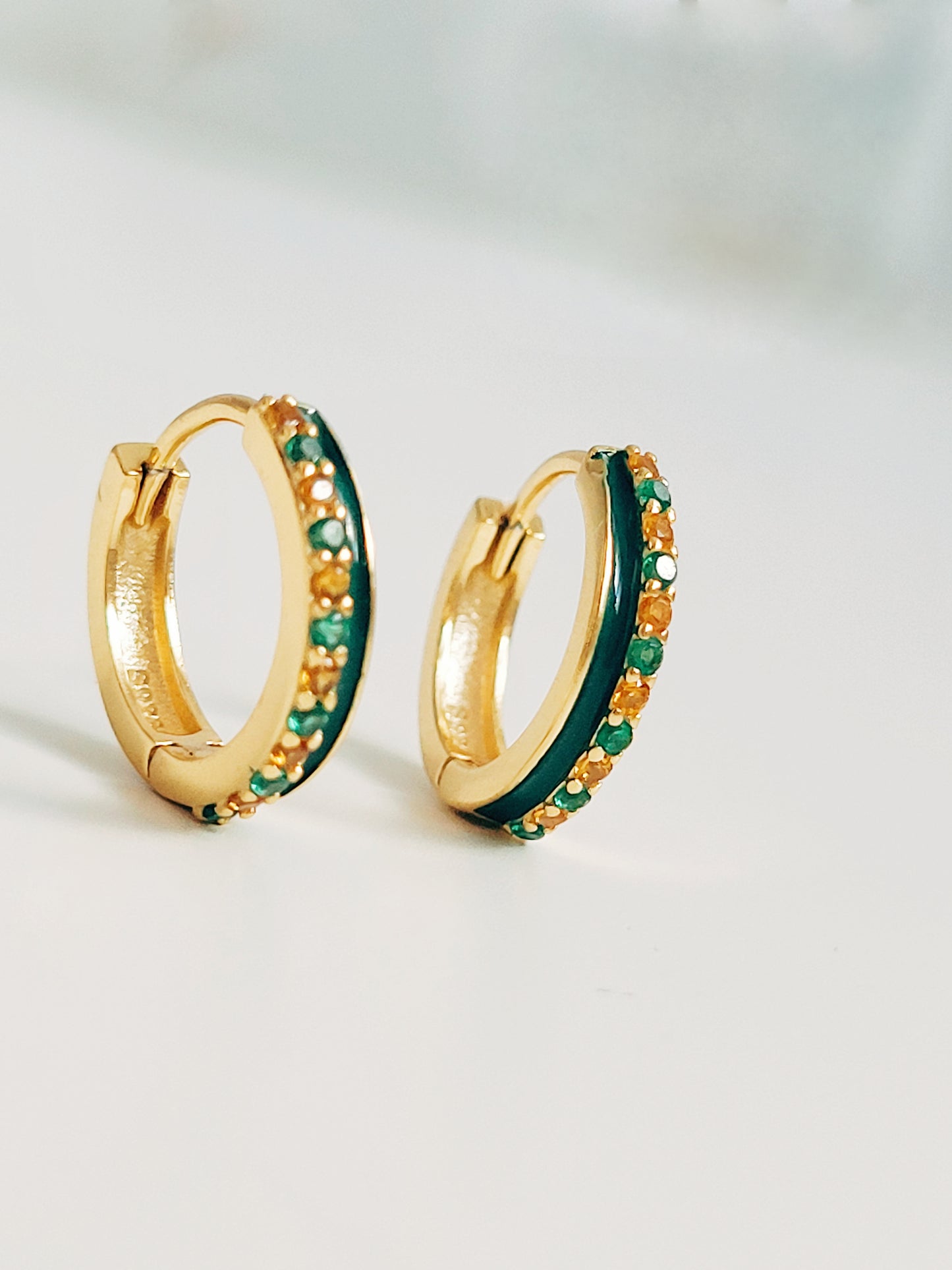 Close-up of emerald green enamel huggie hoop earrings with gold-plated and zircons detailing, showcasing its elegance minimalist style.