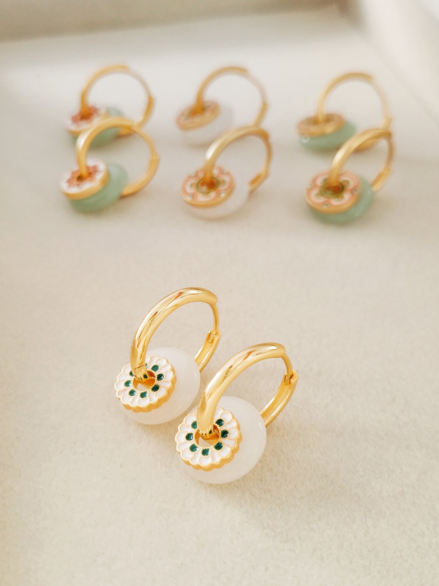 Beautiful gold and white earrings with a floral motif enamel, designed as drop hoops for a trendy and elegant look.