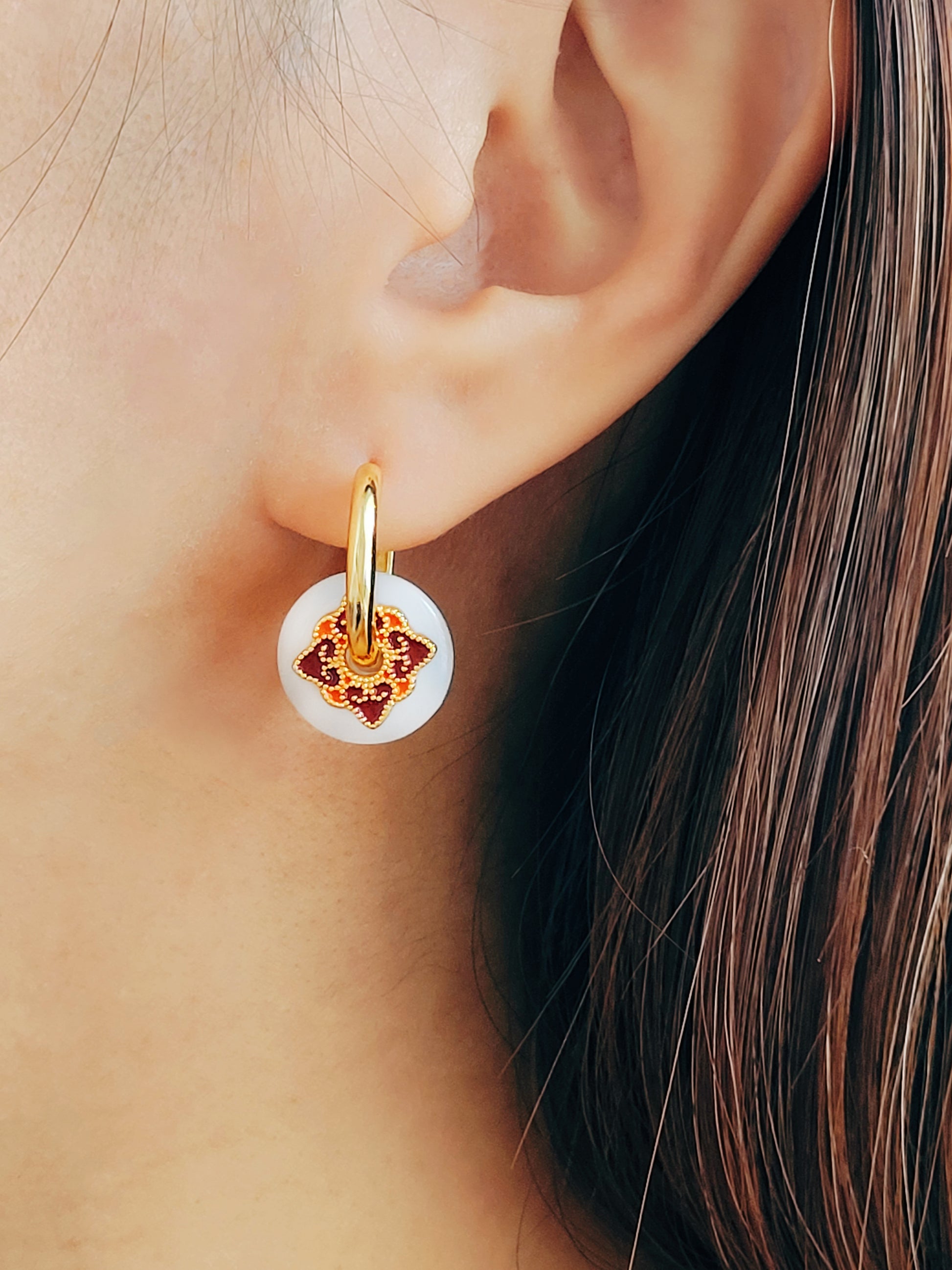 Close up of a woman’s ear wearing a stylish enamel charm earrings with boho flair, inspired by vintage tile designs and crafted for modern wear.