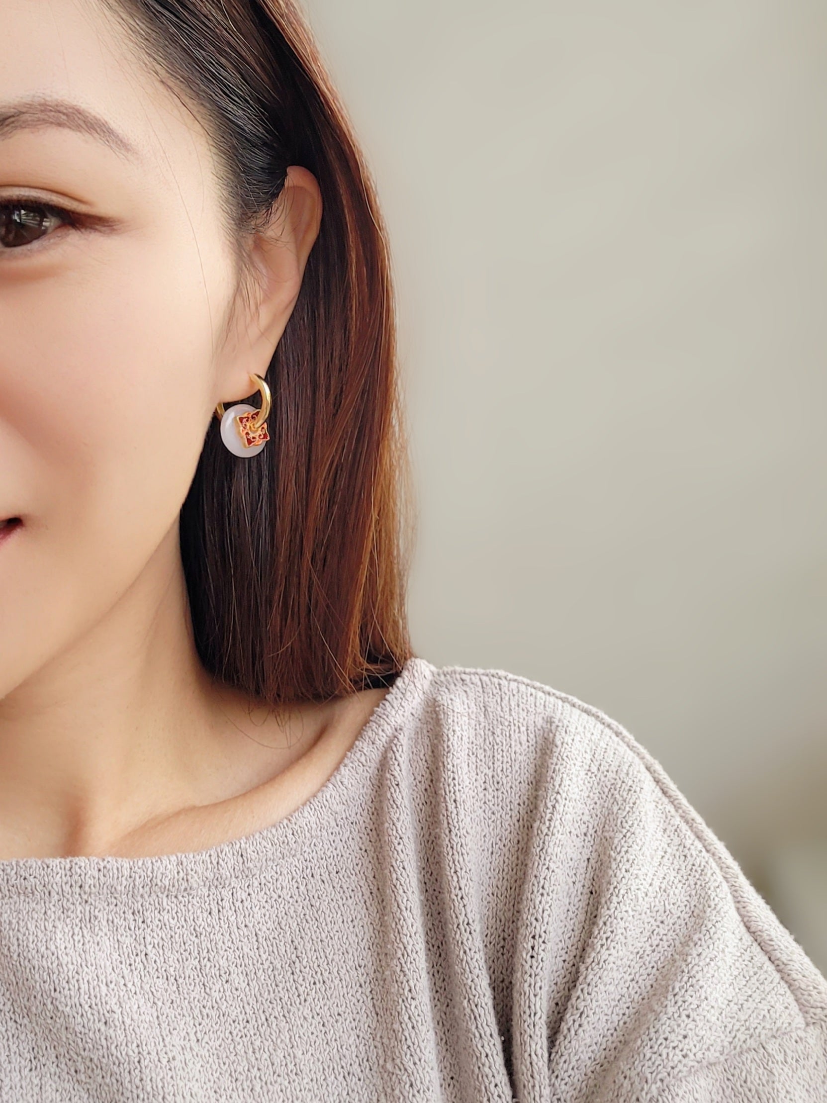 Close up of a woman’s ear wearing a stylish enamel charm earrings with boho flair, inspired by vintage tile designs and crafted for modern wear.