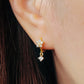 Close-up of a woman wearing a gold flower huggie earrings with clear cubic zirconia stone dangle.
