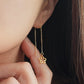 Gold flower-shaped earring worn by a woman with dark hair.