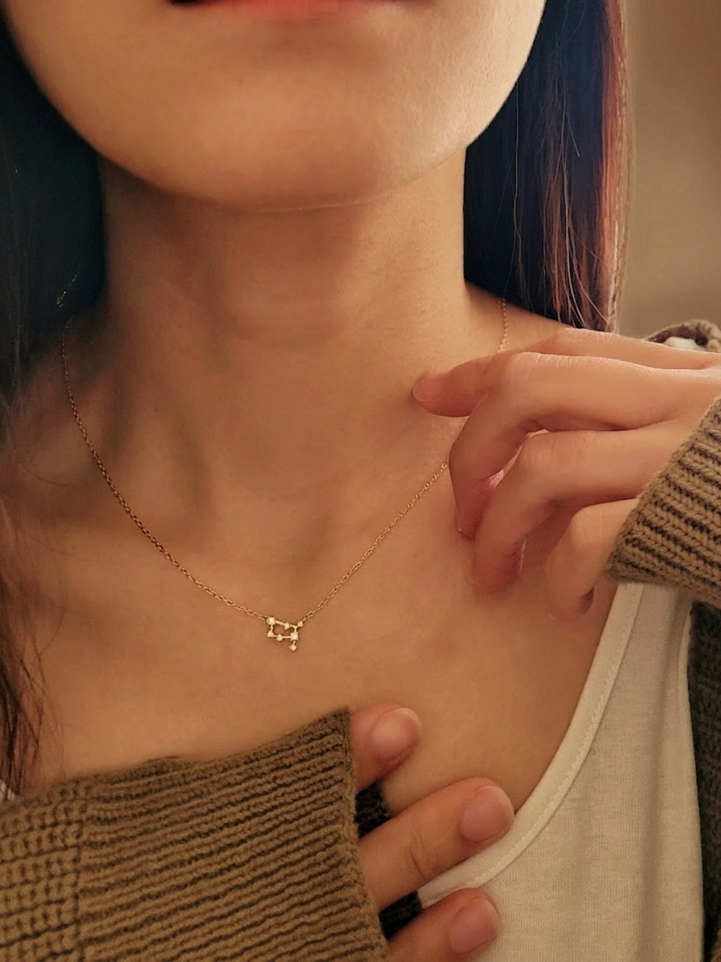 Close-up of a woman wearing an Gemini necklace showcasing the luxury aesthetic and pendant scale. Crafted in gold vermeil, a perfect jewellery gift for her.