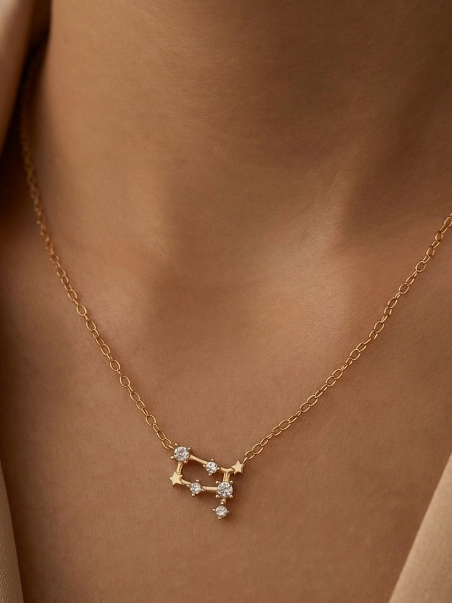 Close-up of a woman wearing an Gemini necklace showcasing the luxury aesthetic and pendant scale. Crafted in gold vermeil, a perfect jewellery gift for her.