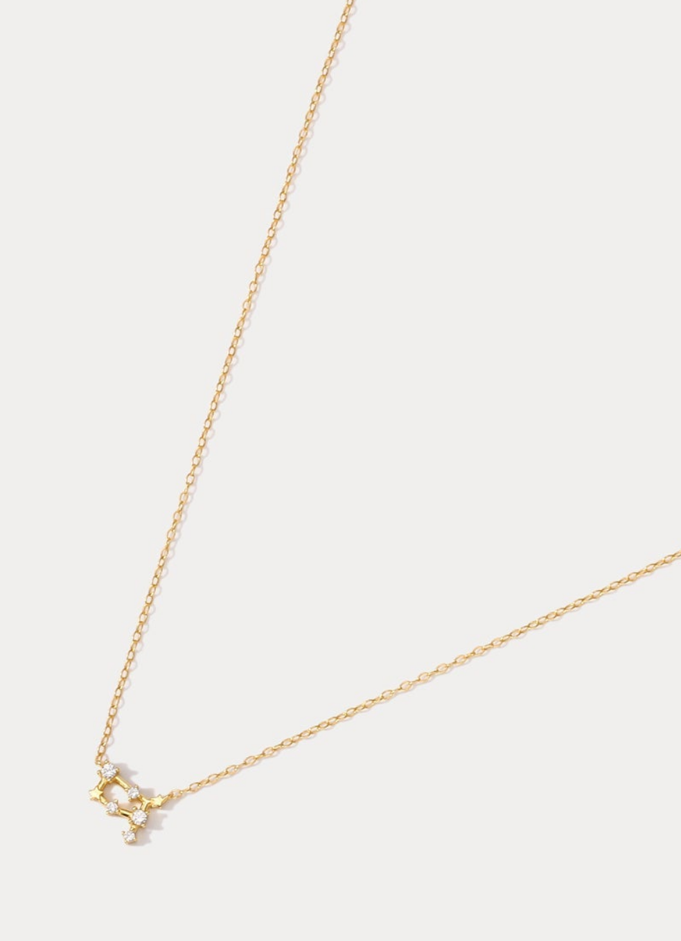 A dainty gold necklace with a pendant featuring a stylized Taurus zodiac constellation sign with sparkling zircons crafted in gold plated sterling silver. Ideal birthday gift for her.