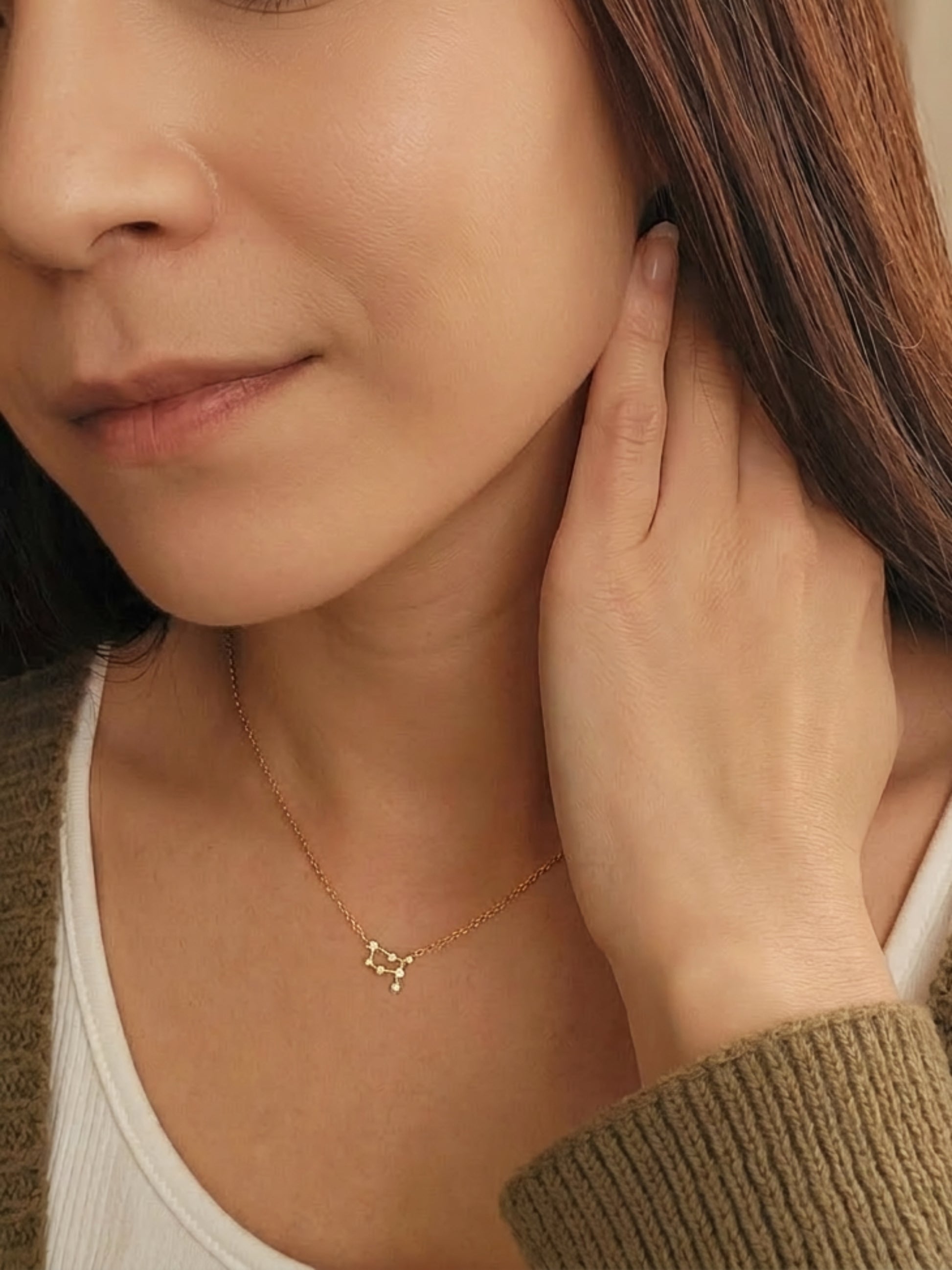 Close-up of a woman wearing an Gemini necklace showcasing the luxury aesthetic and pendant scale. Crafted in gold vermeil, a perfect jewellery gift for her.