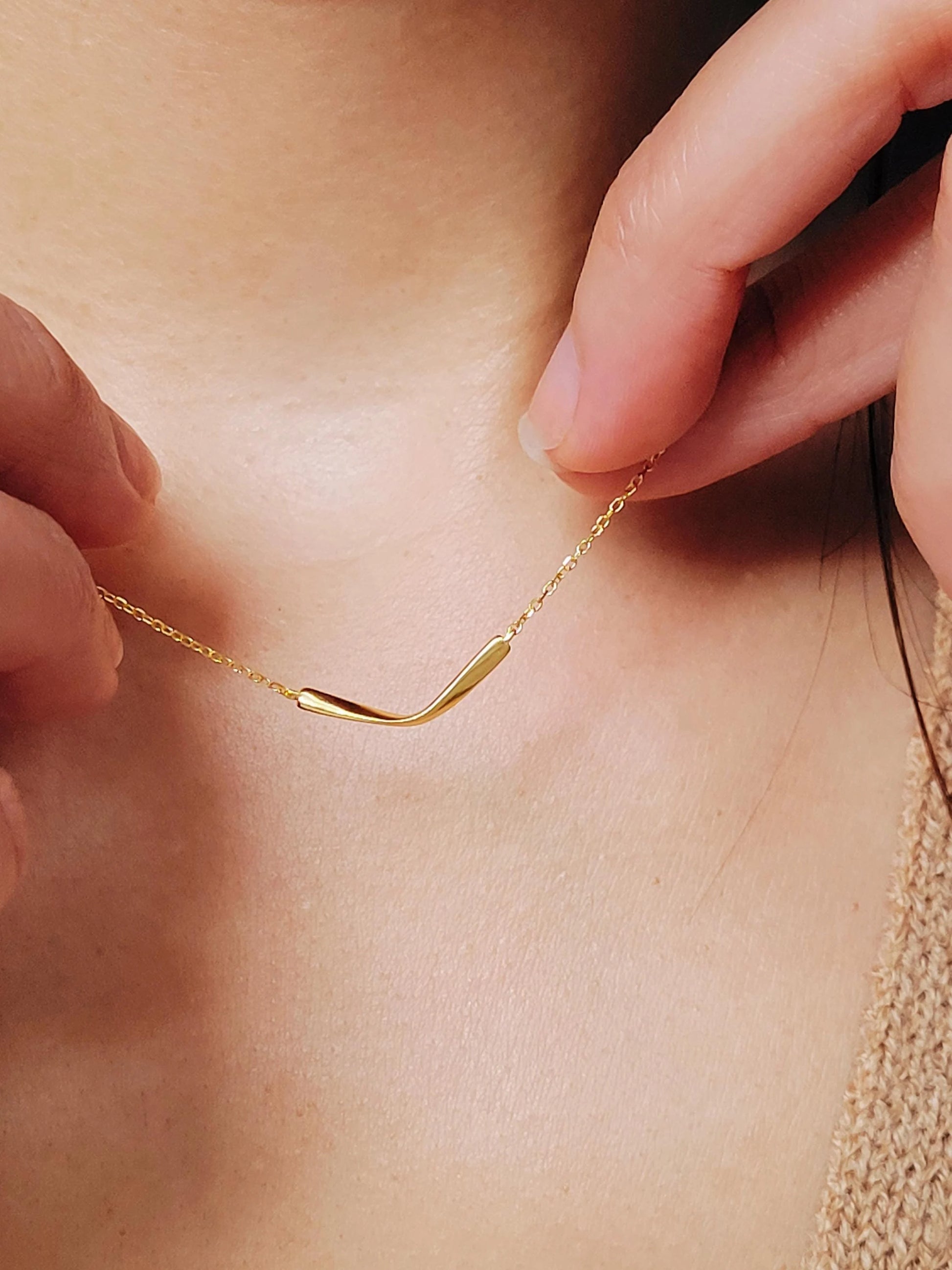 A delicate gold chain necklace with a simple, curved pendant crafted in gold plated sterling silver.