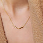 Close up of a woman wearing a simple gold curve bar necklace