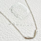 Close up of a dainty silver curve bar necklace crafted in 925 sterling silver displayed on a jewellery box