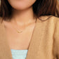 A girl wearing the simple gold bar necklace with beige cardigan, simple and minimalist outfit