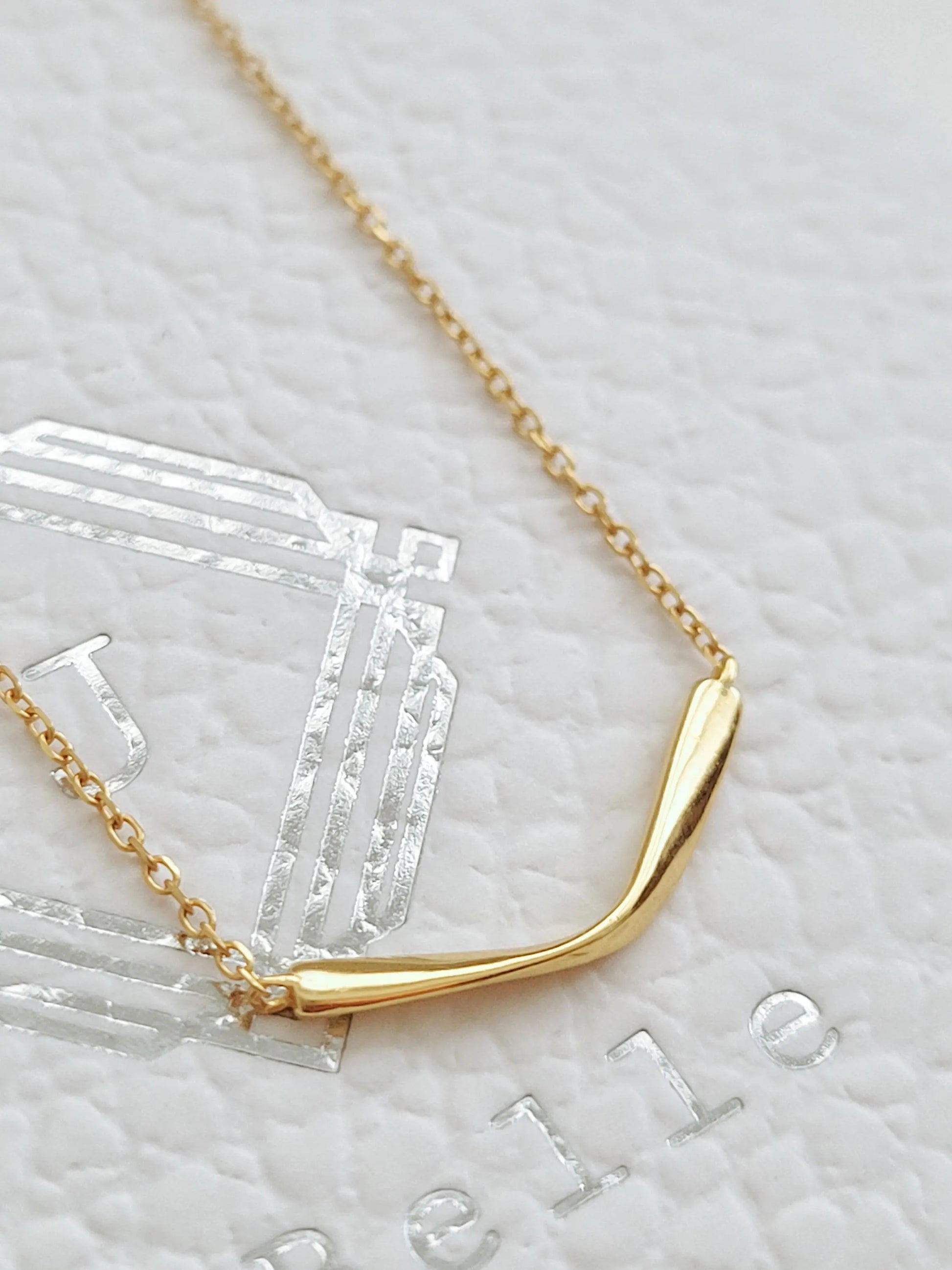 Close up of a simple curve bar necklace on JaBelle Jewellery box