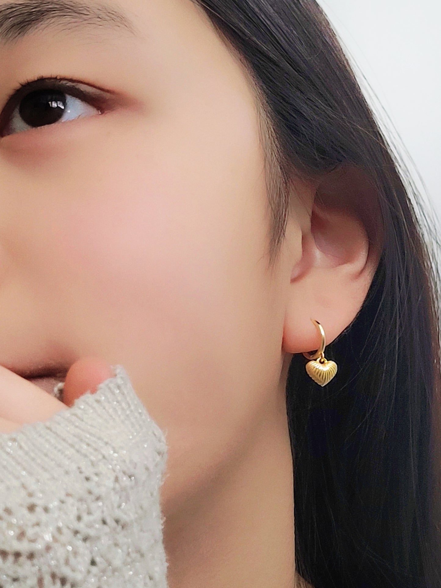 A woman wearing gold plated sterling silver heart dangle earrings. Simple, classic and minimalist design perfect for everyday wear.