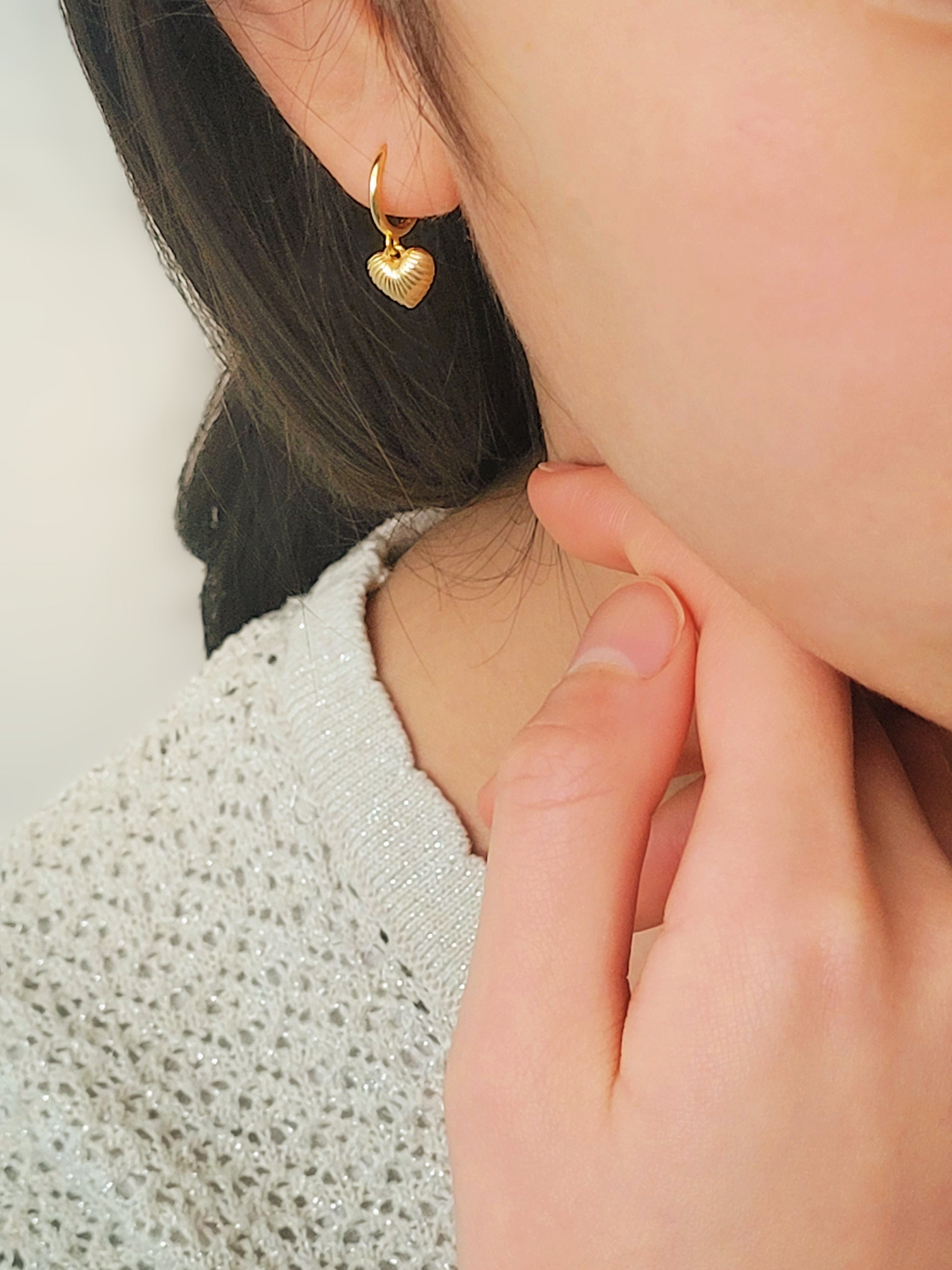 A woman wearing gold plated sterling silver heart dangle earrings. Simple, classic and minimalist design perfect for everyday wear.