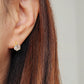 Close-up of a gold vermeil solitaire huggie earring with a large cubic zirconia stone worn on an ear