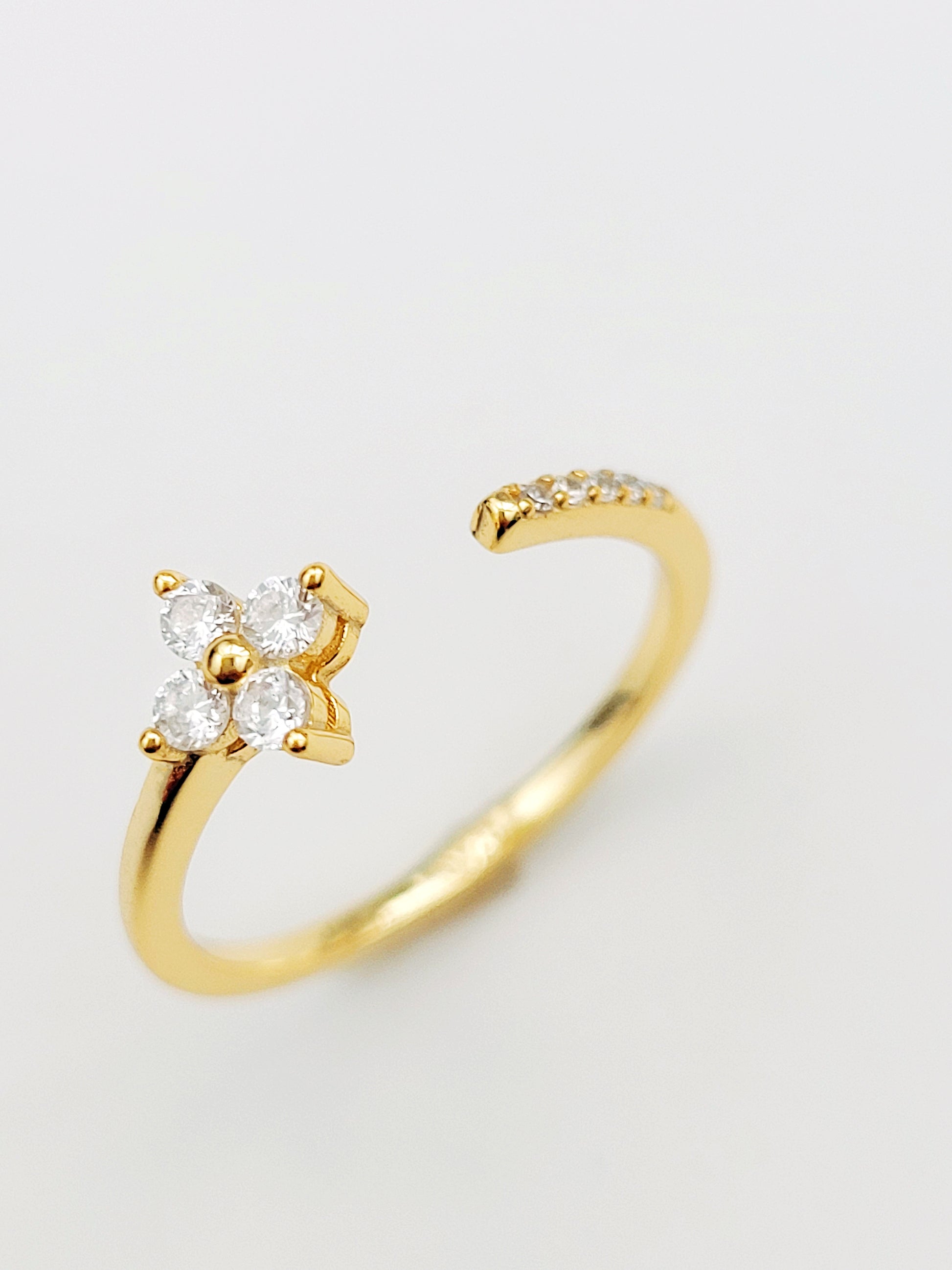 A gold-plated open clover ring featuring a diamond flower design, elegantly showcasing its intricate craftsmanship.