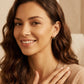 Woman with wavy brown hair smiling softly, wearing the halo drop stud earrings with beige sweater.