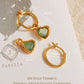 Gold hoop earrings with green crystal quartz on a textured surface
