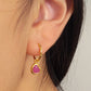 Gold earring with a pink heart crystal quartz worn by a woman