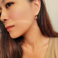 Woman wearing a pink heart gold hoop earrings, dainty and minimalist