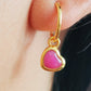 Close up of a woman wearing pink heart earrings crafted in gold plated sterling silver and natural quartz gemstone