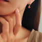 A woman wearing pink heart dangle earrings, dainty and delicate