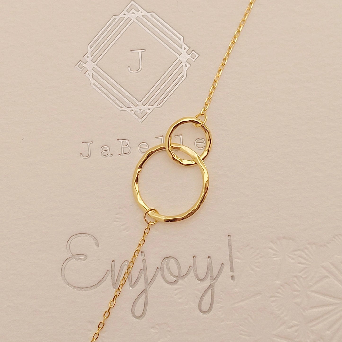 Delicate gold interlocking circle bracelet showcased on a paper, highlighting its simple and timeless design, perfect for everyday wear or gifting