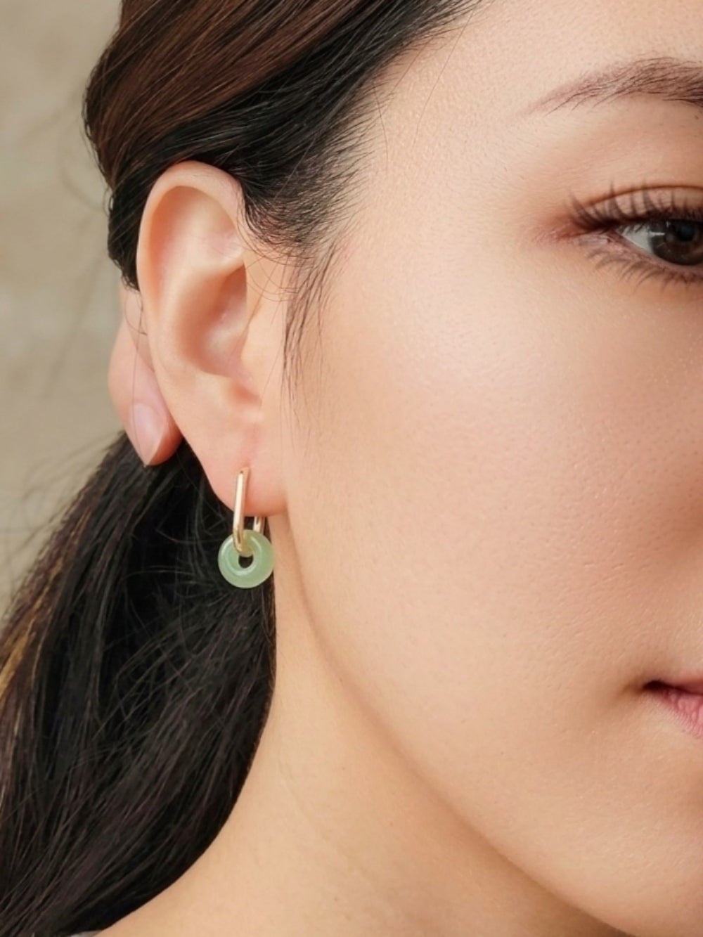 Close up of a woman wearing dainty jade hoop earrings, minimalist and delicate genuine jade jewellery.