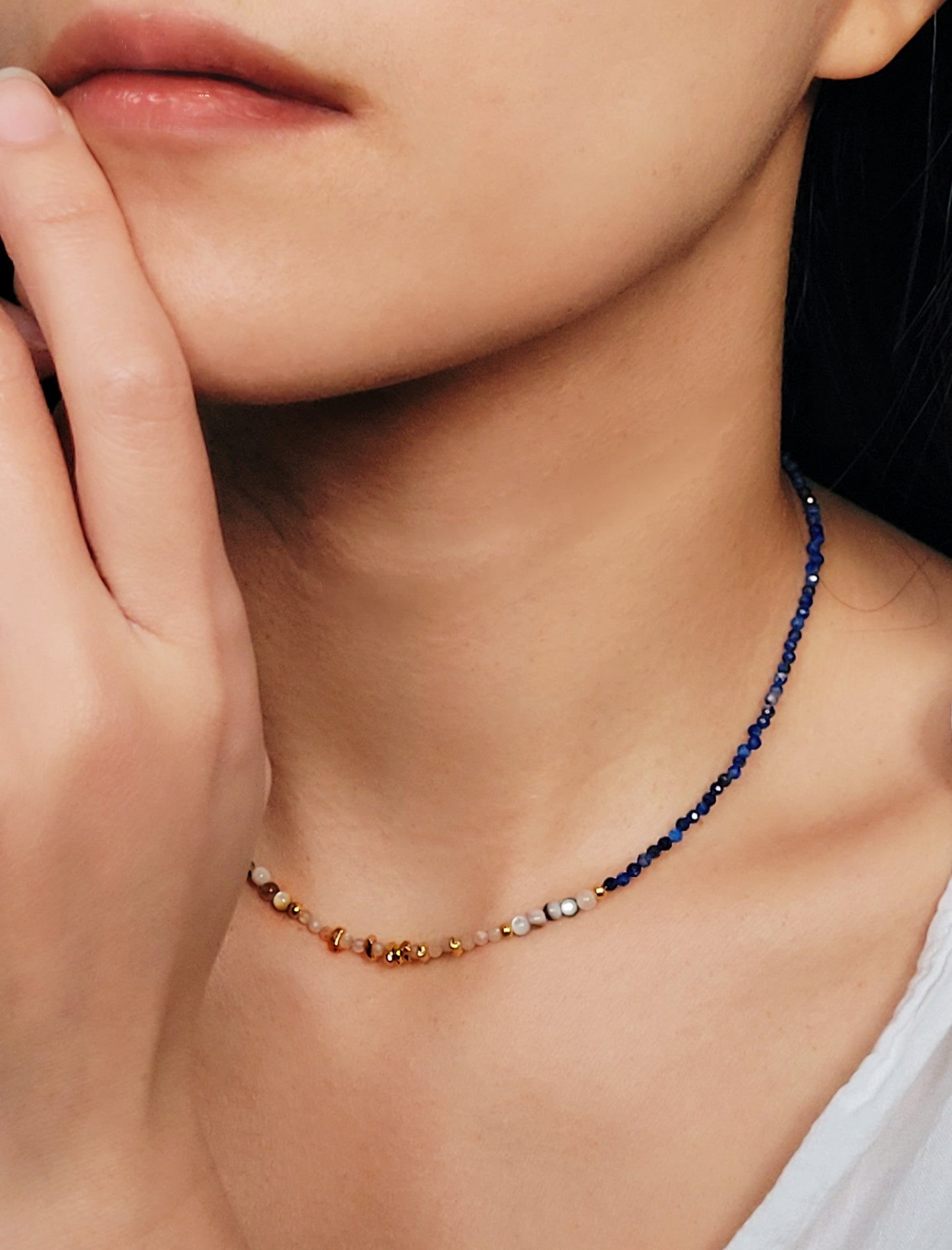 Close up of a woman wearing blue lapis lazuli beaded necklace featuring a mix of gemstones and elegant gold vermeil beads. Handcrafted for a unique, luxurious look. Perfect for any occasion. Stand out in style with this exquisite piece!