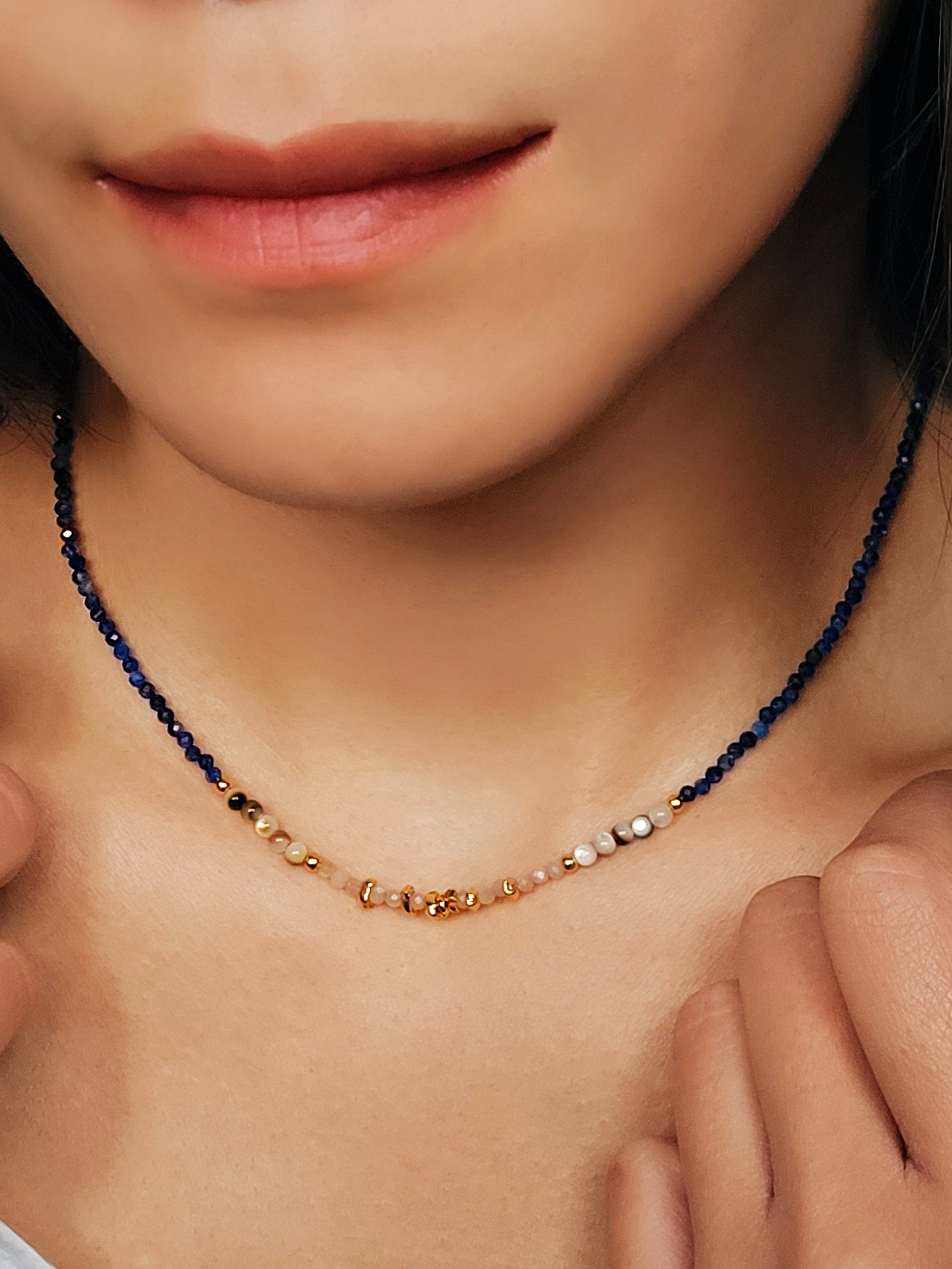 Close up of a woman wearing blue lapis lazuli beaded necklace featuring a mix of gemstones and elegant gold vermeil beads. Handcrafted for a unique, luxurious look. Perfect for any occasion. Stand out in style with this exquisite piece!