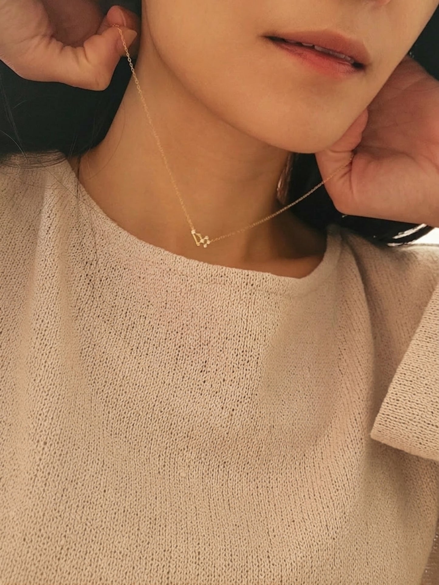 Close-up of a person wearing a delicate necklace with a small pendant featuring Leo constellation star sign, crafted in gold plated sterling silver.