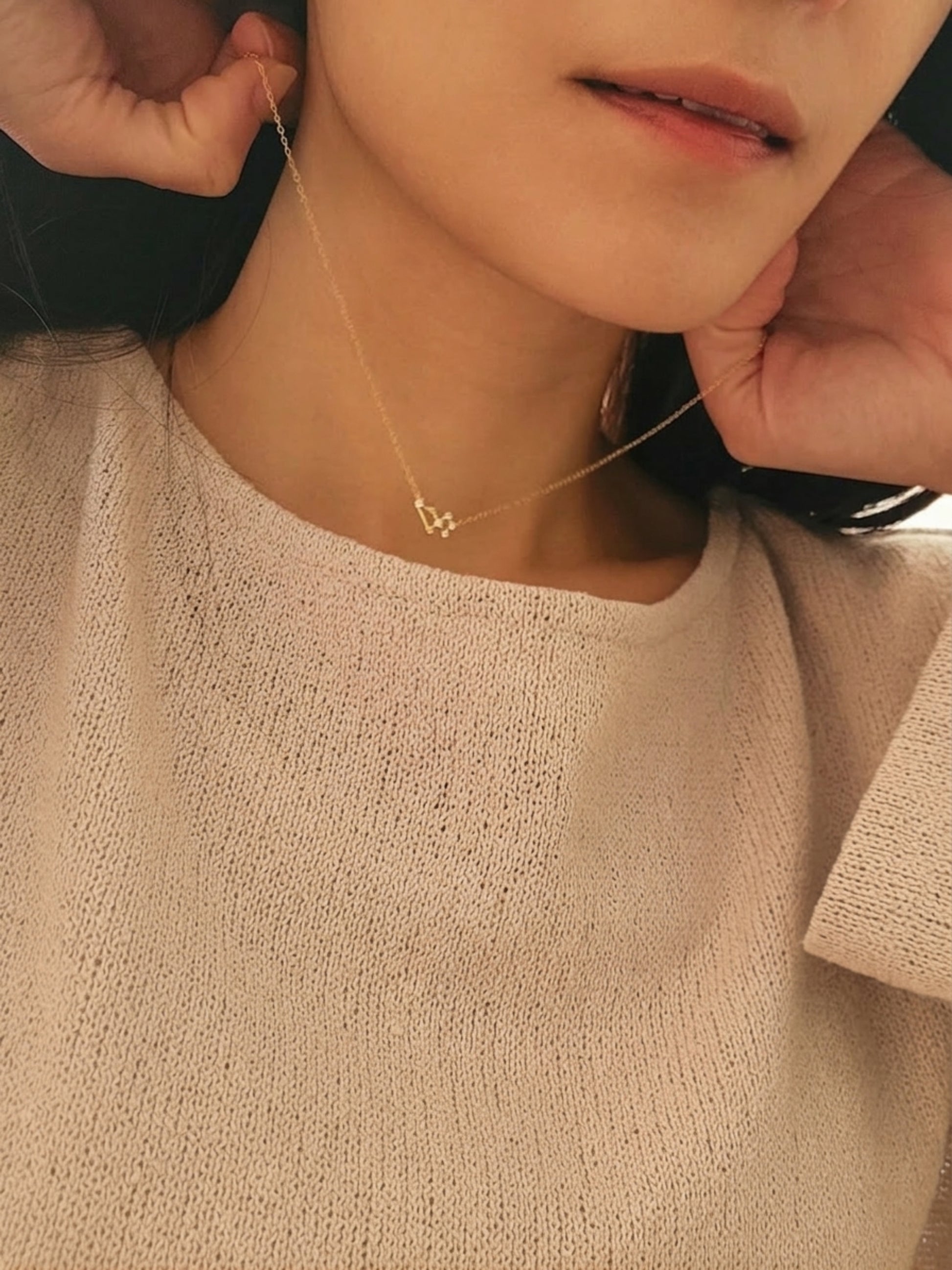 Close-up of a person wearing a delicate necklace with a small pendant featuring Leo constellation star sign, crafted in gold plated sterling silver.