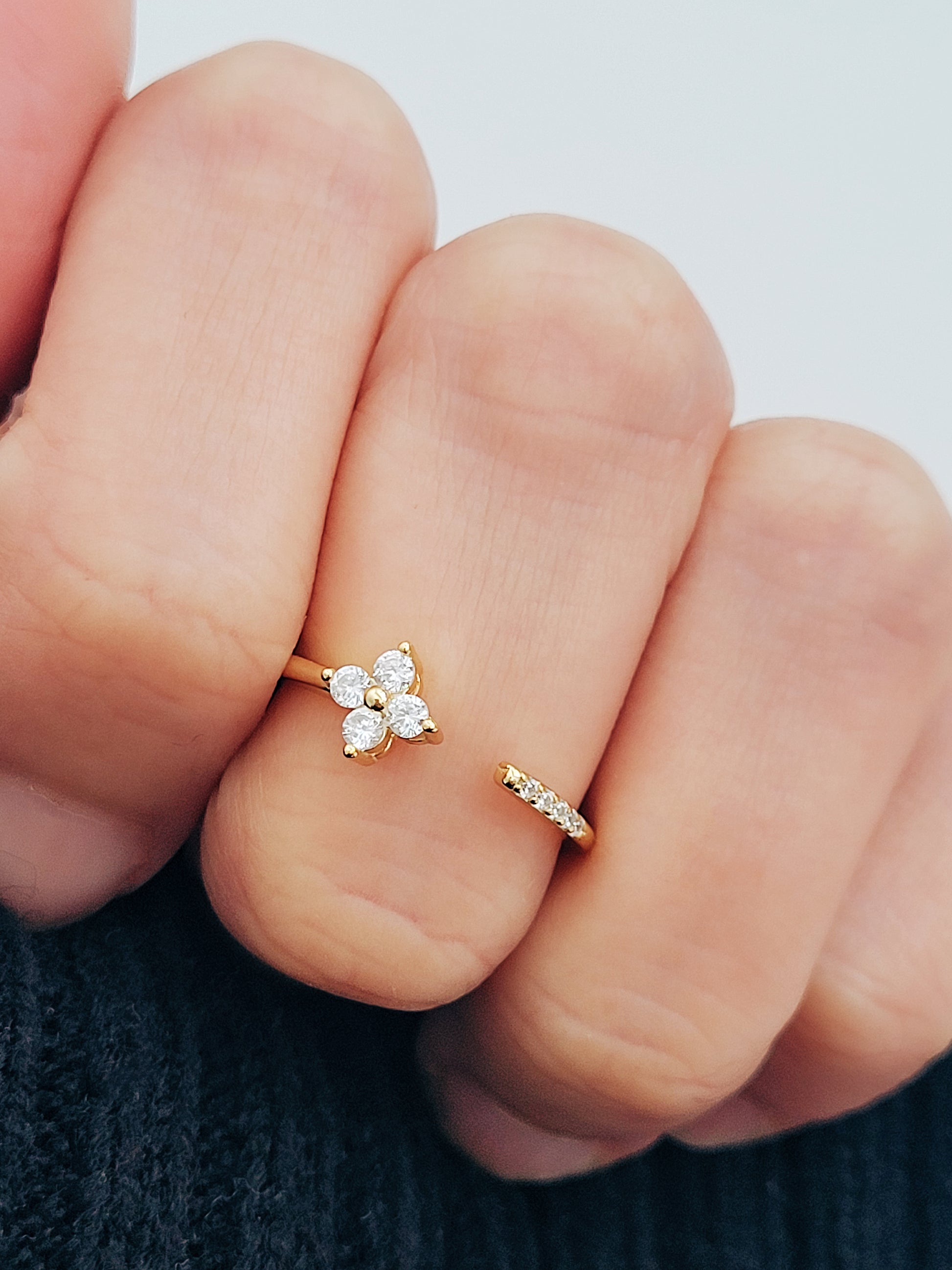 Close-up of a woman's hand showcasing a dainty gold Clover ring featuring four brilliant diamonds.