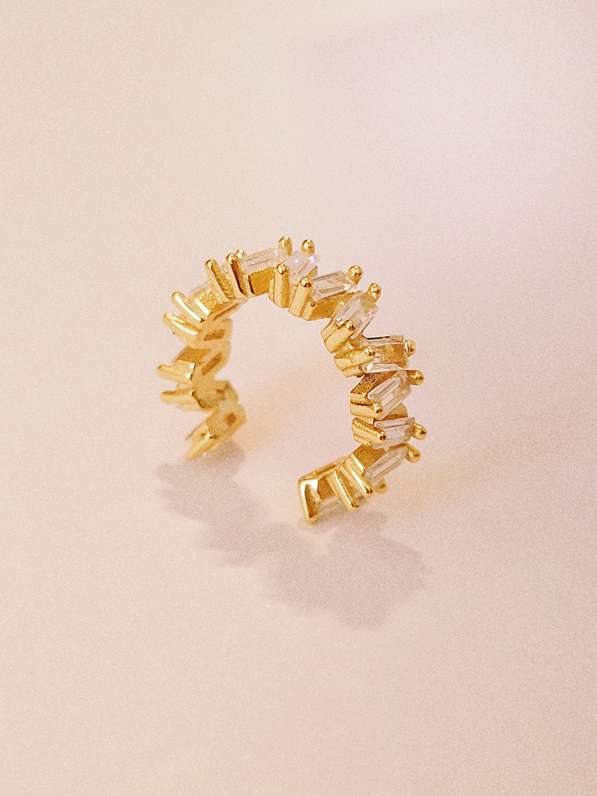 18ct gold vermeil ear cuff featuring a sleek, open design with multiple clear baguette-cut gemstones. The cuff has a modern, minimalist style and does not require piercing, making it a versatile accessory for cartilage or earlobe wear.