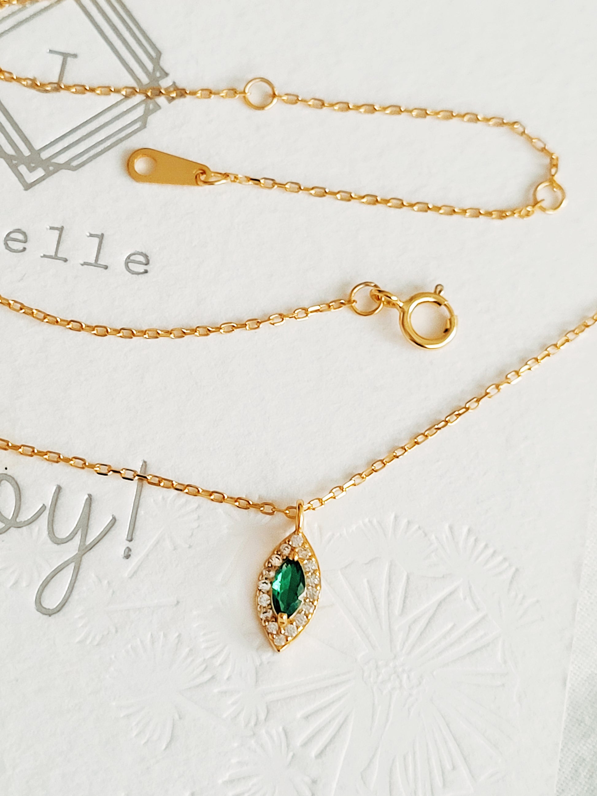 Close-up of a marquise emerald green evil eye pendant necklace on a delicate gold chain, showcasing its dainty and elegant vintage-inspired design.